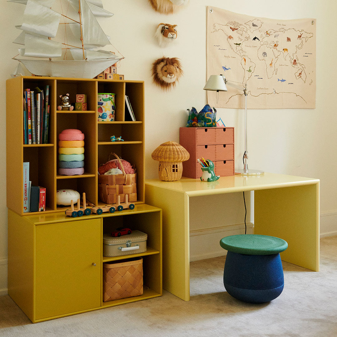 Stapelstein speelelement in blauw en groen gebruikt als krukje in een kinderkamer.