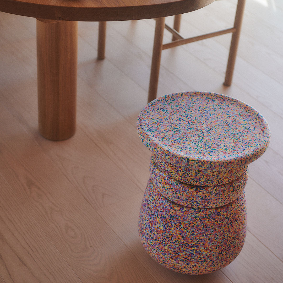 Een stapelstein dynamic confetti element staat op een houten vloer, gezien van bovenaf.