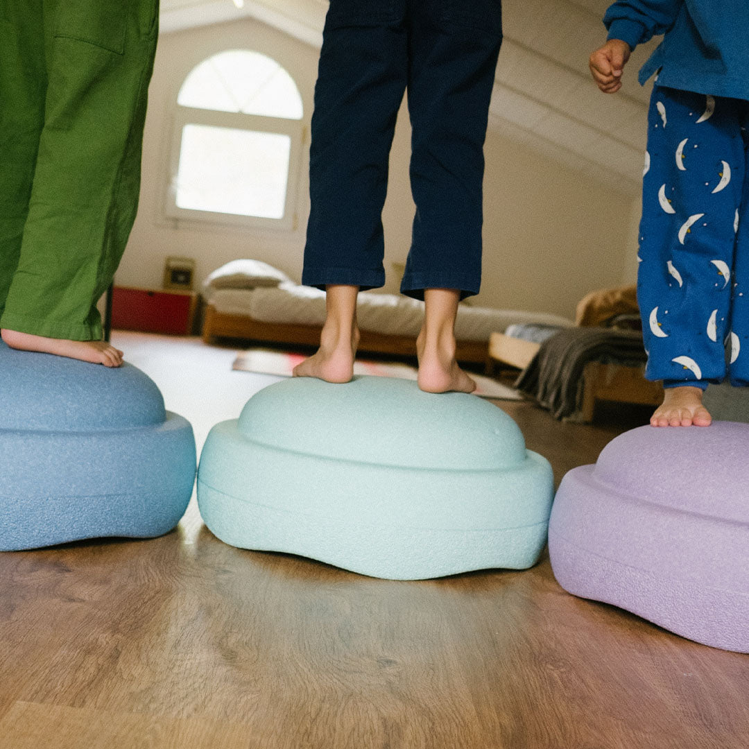 Blote kindervoeten staan op drie gekleurde stapelstein schuimrubberblokken.