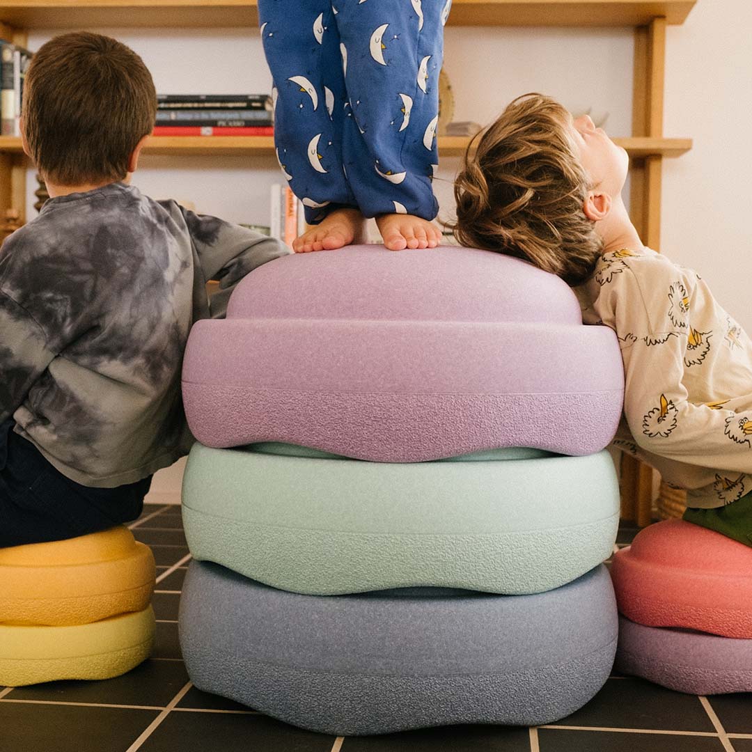 Drie kinderen spelen met een stapel gekleurde stapelstein schuimrubberblokken.