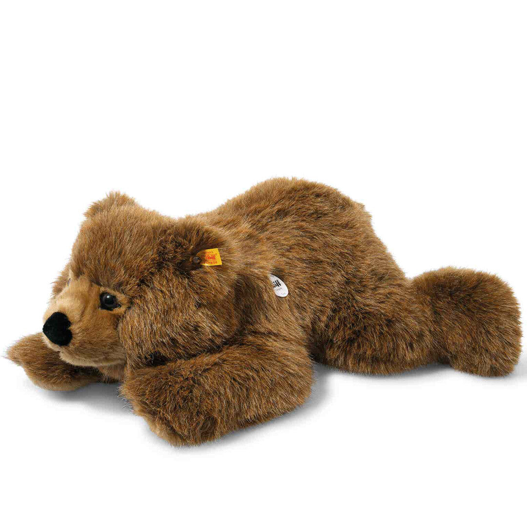 Steiff knuffel teddybeer Urs, bruin en liggend, schuin van bovenaf gefotografeerd.