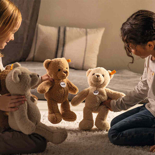 Twee kinderen spelen met twee Steiff pluchen teddyberen in een slaapkamer.