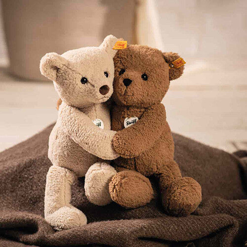 Twee Steiff pluchen teddyberen, een lichte en een donkere, knuffelen elkaar op een bruine deken.