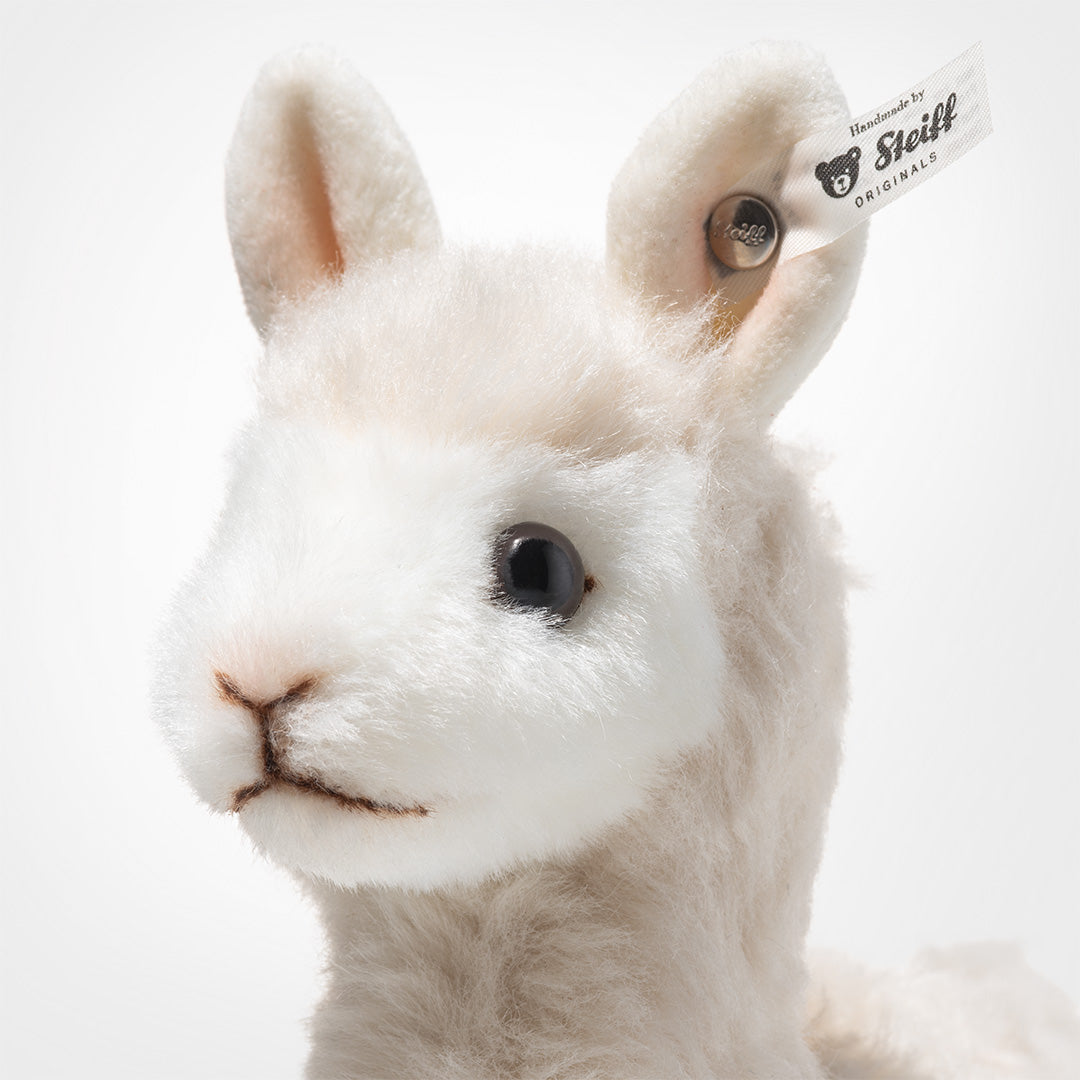 Detailfoto van de kop van de Steiff knuffelalpaca met het merklabel in het oor.