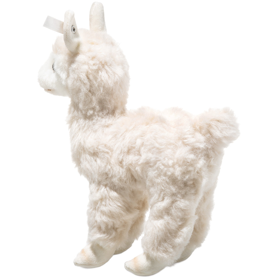Steiff knuffelalpaca in crème kleur, staand en van de linkerzijkant gefotografeerd.