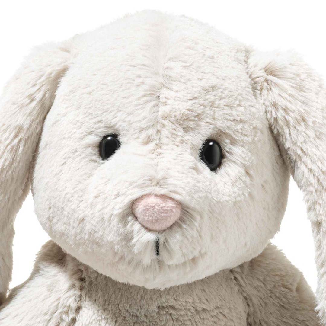 Close-up van het gezicht van het Steiff pluchen knuffelkonijn Hoppi met zwarte ogen en een roze neus.