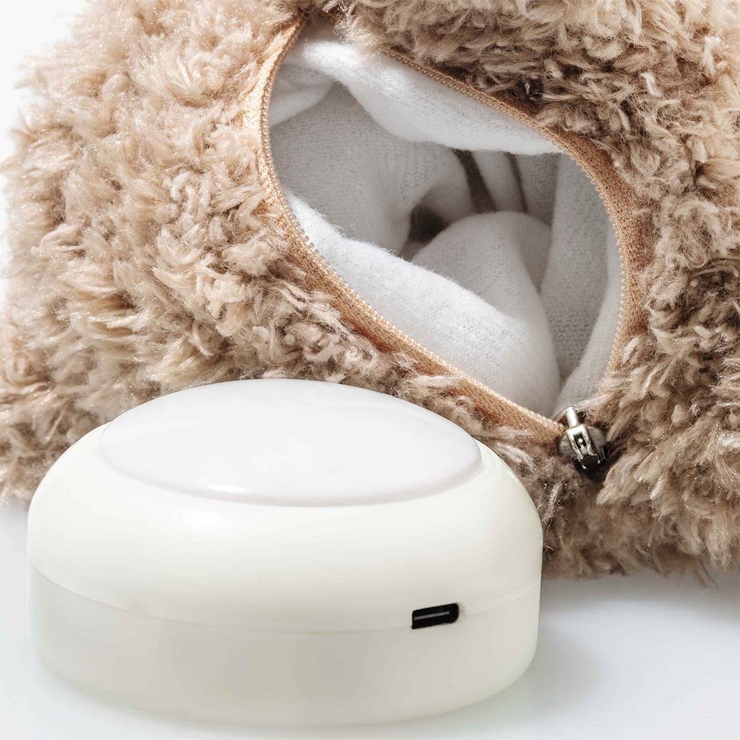 Detail van de Steiff teddybeer met open rits aan de achterkant en de witte oplaadbare lichtmodule ernaast.
