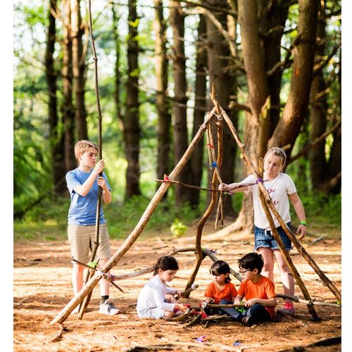 Vier kinderen bouwen een fort van takken in het bos met behulp van stick-lets bouwsetspeelgoed.