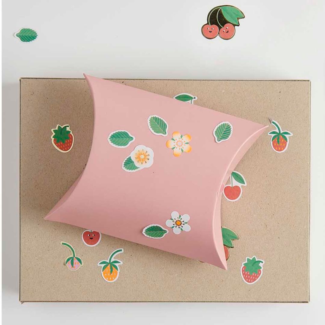 Roze kussendoos en bruin karton versierd met fruit- en bloemenstickers.