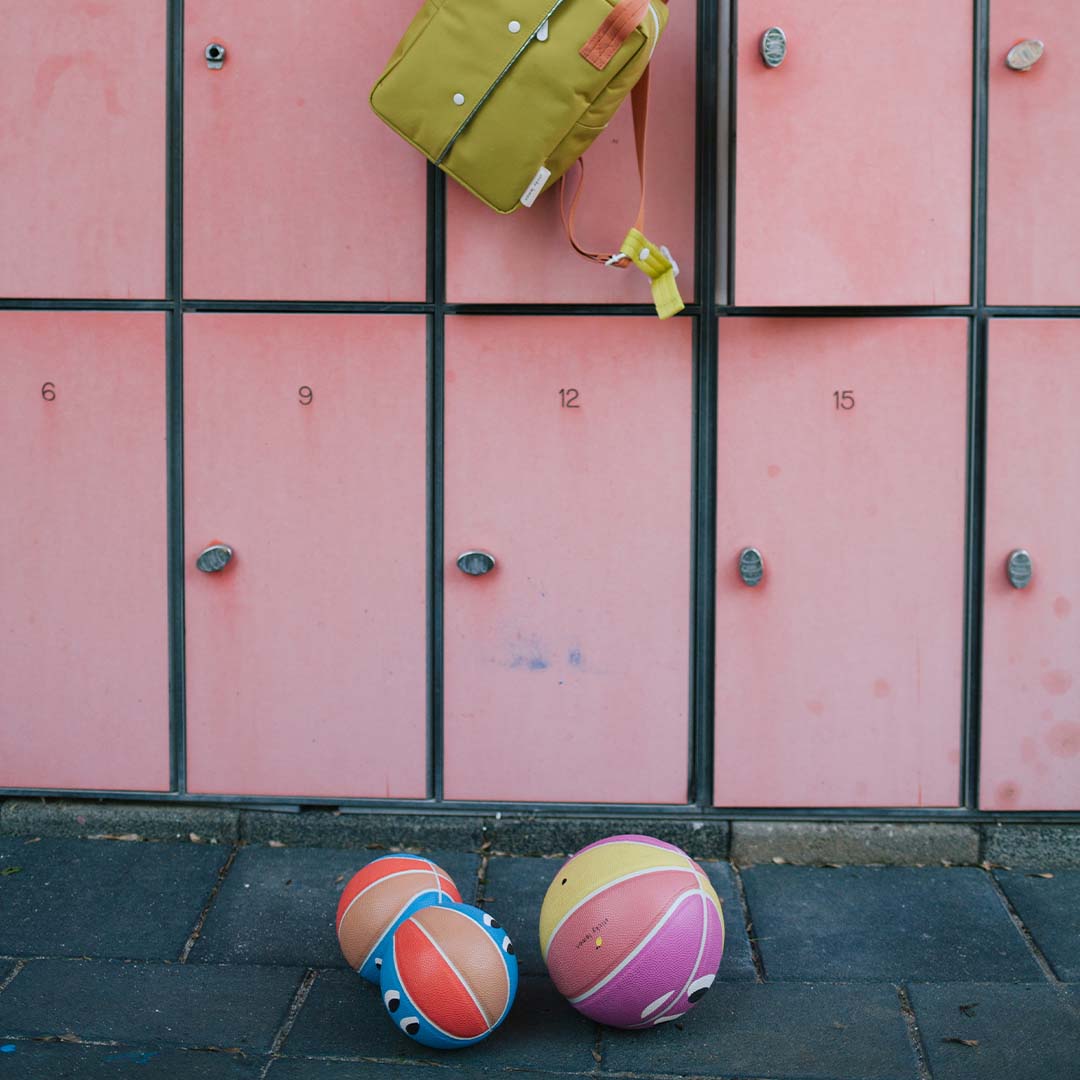 Twee sticky lemon speelballen met gezichtjes liggen op de grond voor roze kluisjes.