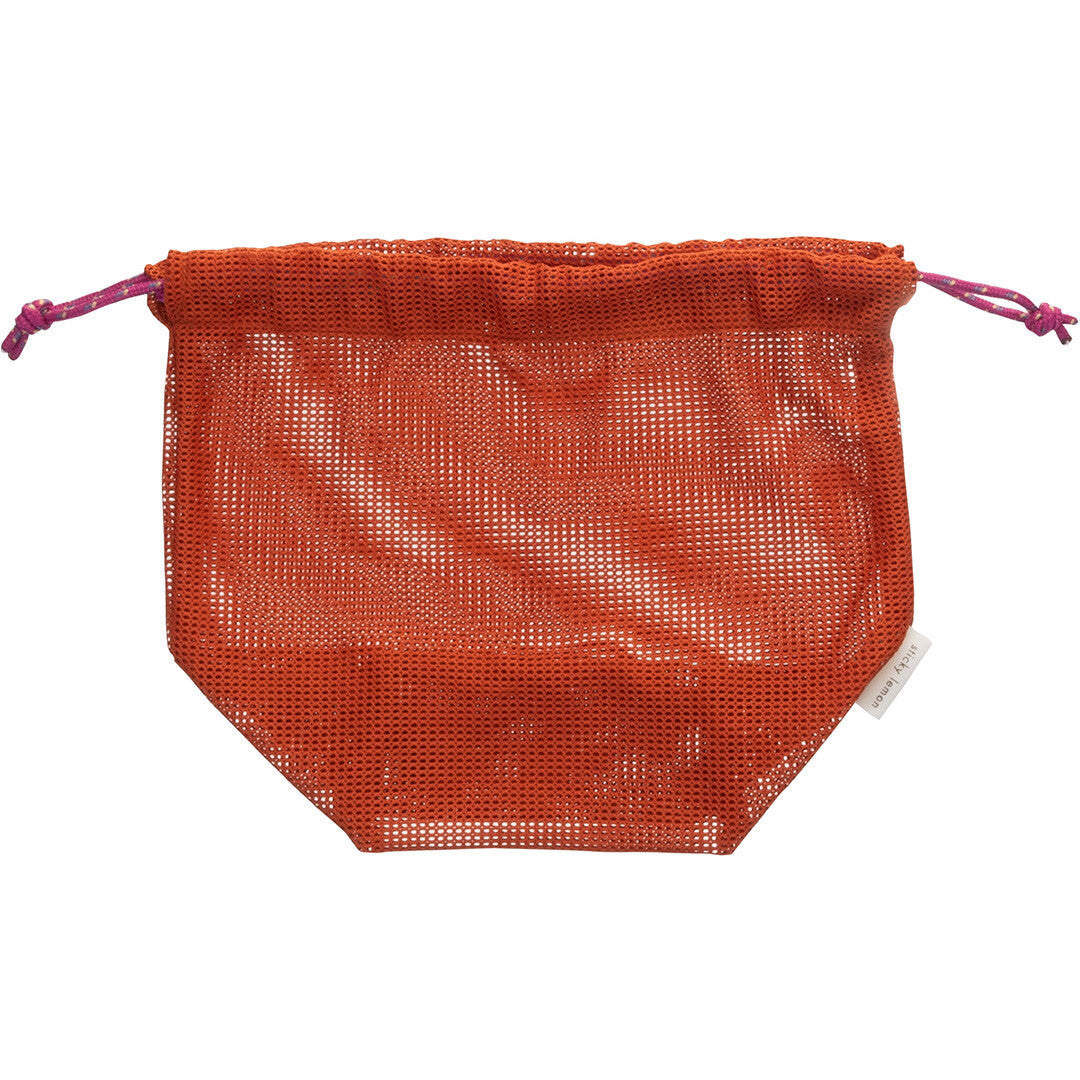 Een lege oranje nettas met trekkoord ligt plat op een witte achtergrond.