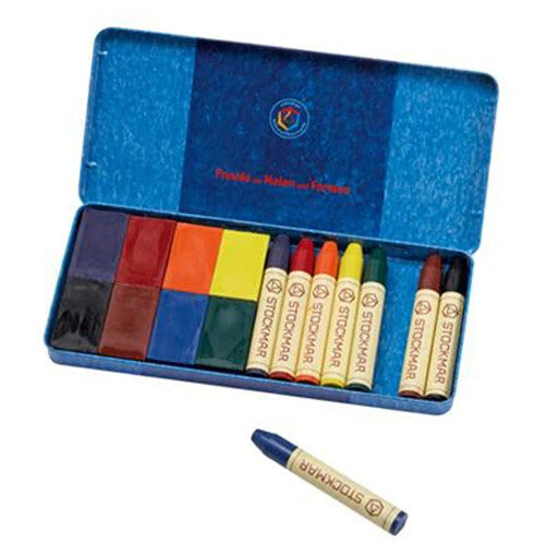Stockmar waskrijt set met blokjes en stiftjes in een open blauwe tinnen doos, met een losse blauwe wasstift ernaast.