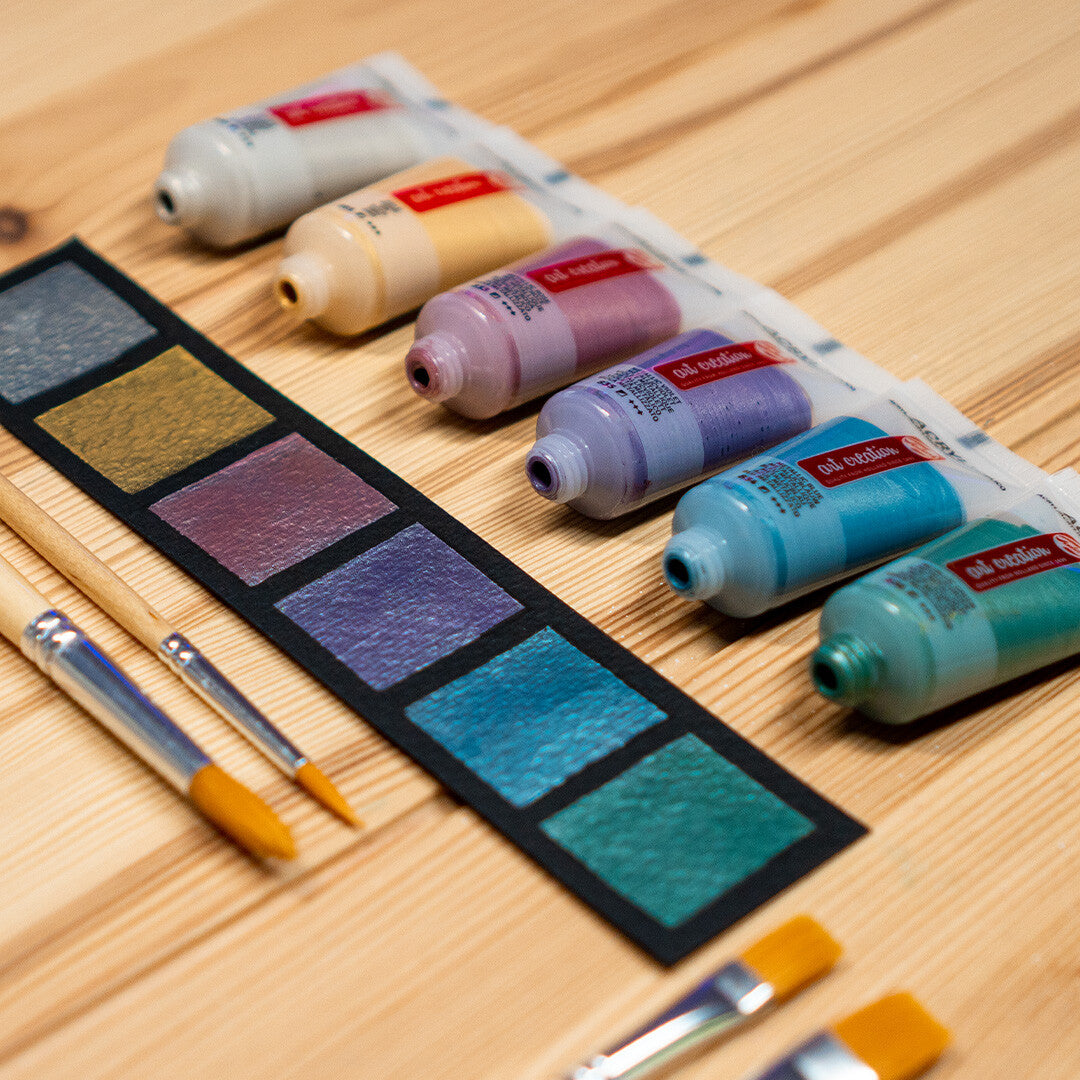 Tubes Talens Art Creation metallic acrylverf en verfmonsters met penselen op een houten ondergrond.
