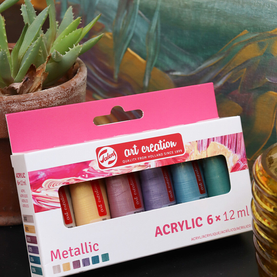 De Talens Art Creation verpakking met zes tubes metallic acrylverf staat op een donkere ondergrond.