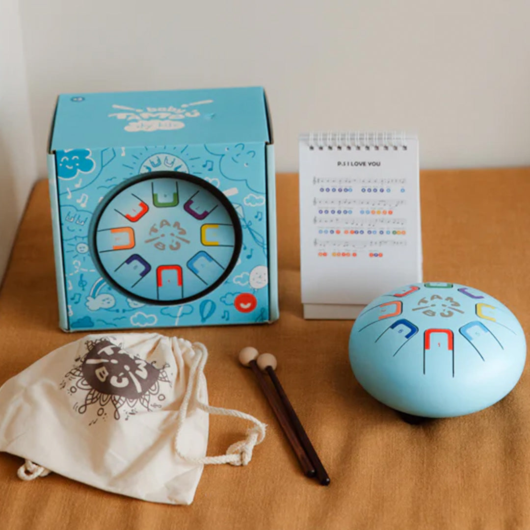 De tambu tongtrommel set met de blauwe trommel, verpakking, draagtas, mallets en muziekstandaard.