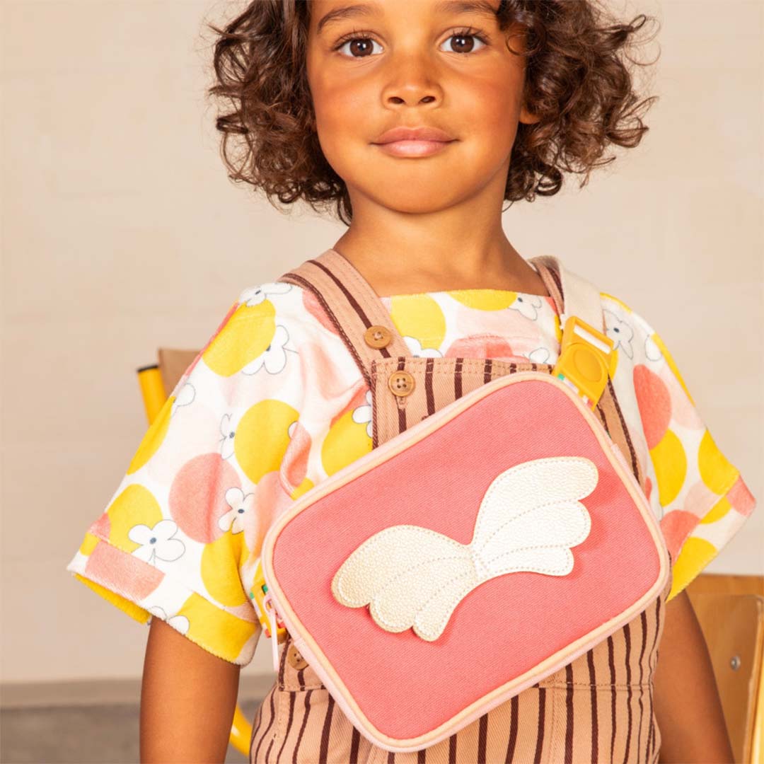 Een kind draagt het Lilliputiens roze kindertasje met vleugels als crossbody tasje.