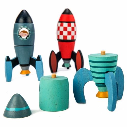 Twee complete Tender Leaf Toys houten raketten en de losse onderdelen van een derde raket, die het bouwprincipe tonen.