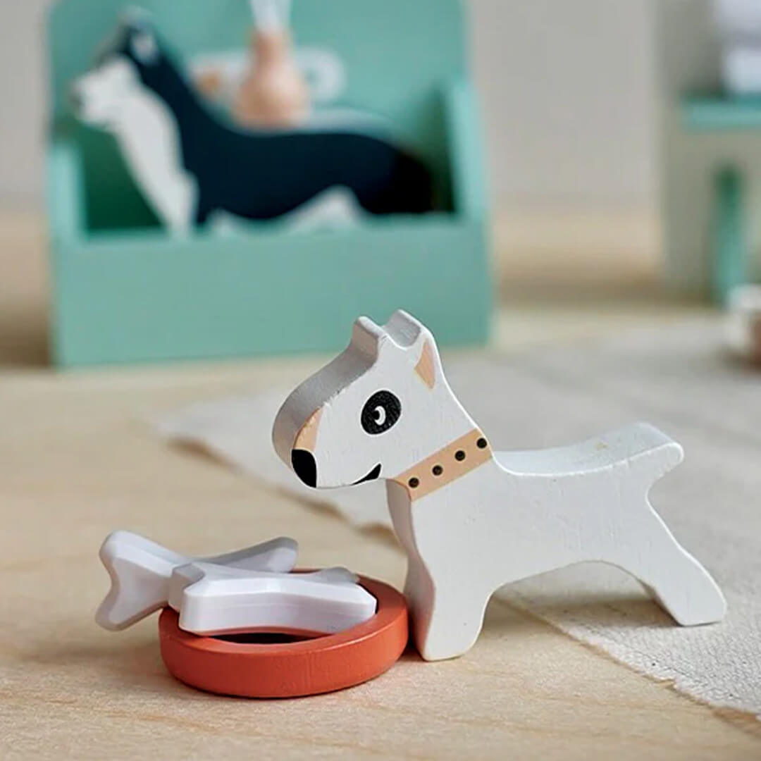 Detailopname van een wit houten hondje naast een voerbak met botjes uit de Tender Leaf Toys hondentrimsalon speelset.