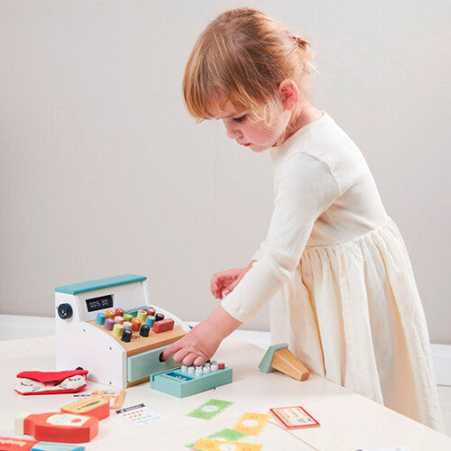 Een kind speelt met de Tender Leaf Toys houten speelgoedkassa en drukt op de knoppen.
