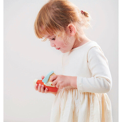 Een kind houdt de houten scanner van de Tender Leaf Toys speelgoedkassa in haar handen.