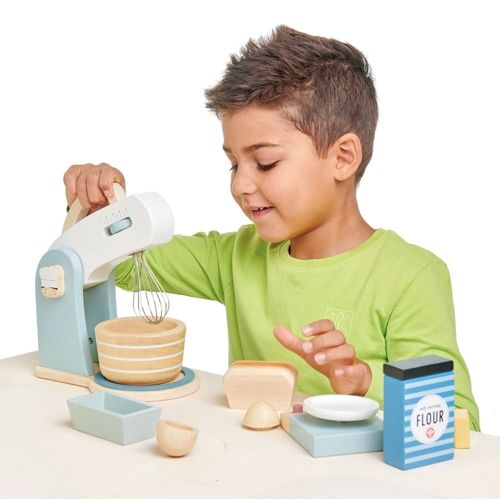 Een lachend kind bedient de Tender Leaf Toys houten keukenmachine van de bakset.