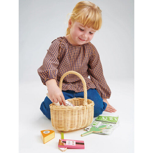 Een kind speelt op de grond met het Tender Leaf Toys speelgoed boodschappenmandje en houten etenswaren.