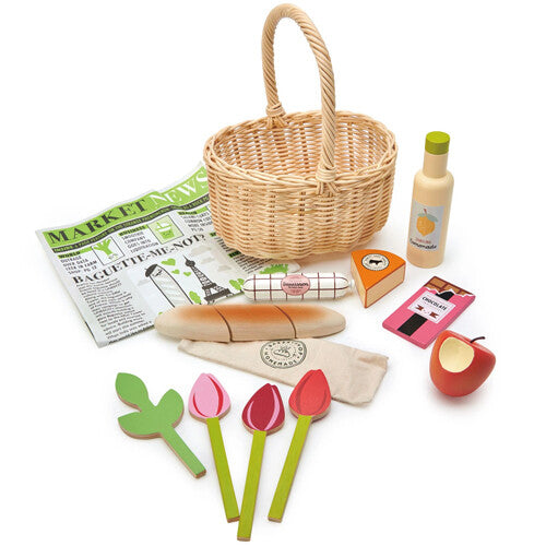 De complete Tender Leaf Toys speelgoed boodschappenmandje set met de rotan mand en alle houten en stoffen speelgoed etenswaren ernaast.