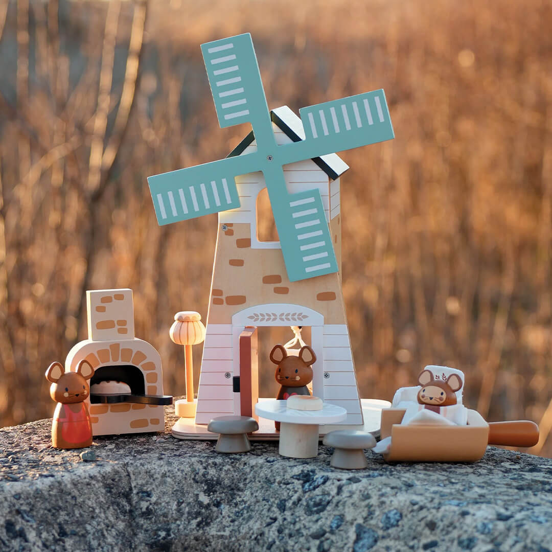 Tender Leaf Toys houten molen speelset met muizenfiguren en bakkerijaccessoires buiten op een steen.