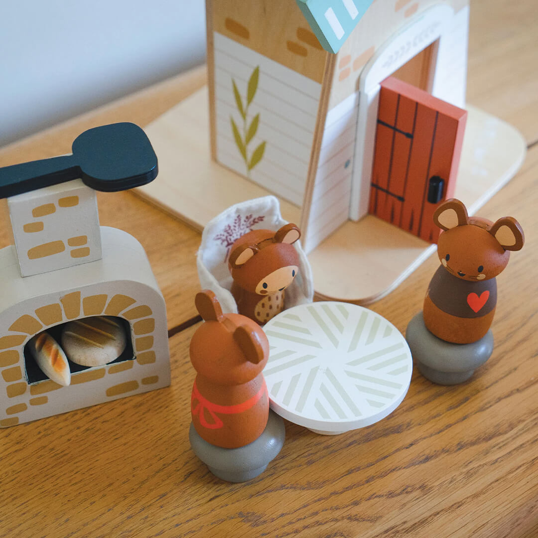Detail van de Tender Leaf Toys houten molen speelset met oven, tafel en drie muizenfiguren op een houten ondergrond.