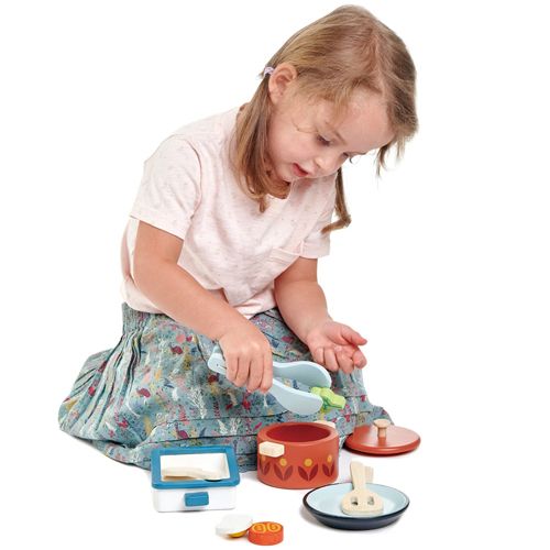Een kind speelt met de Tender Leaf Toys houten speelgoedkeuken pannenset.