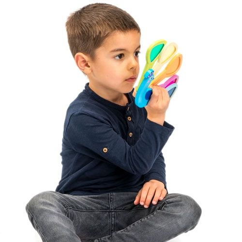 Een jongen bekijkt het Tender Leaf Toys houten pauw visueel speelgoed met gekleurde staartveren.