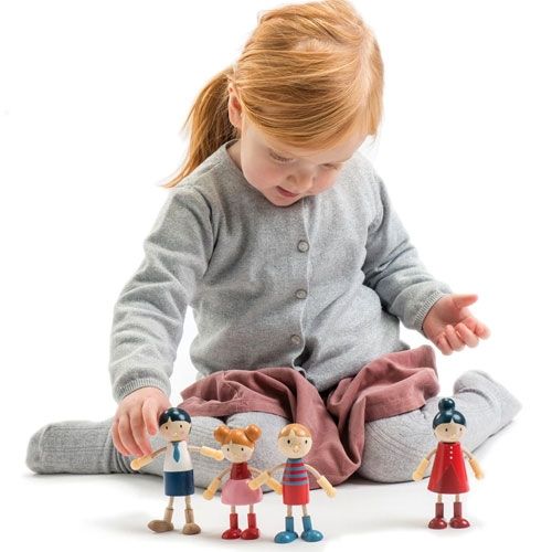Een kind speelt op de grond met de vier houten poppenhuispoppen van de familie.