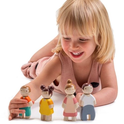 Een lachend kind speelt met de vier houten poppenhuispoppen.