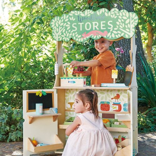 Twee kinderen spelen met het Tender Leaf Toys houten winkeltje in bosdieren thema, met speelgoedfruit.