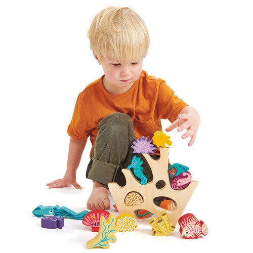 Een jong kind speelt met het Tender Leaf Toys houten stapelspeelgoed met zeedieren en koraal.