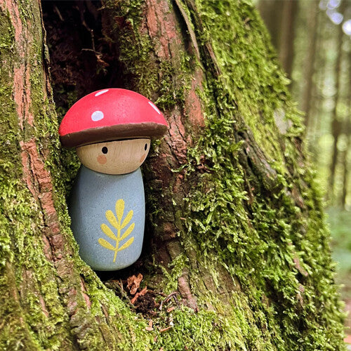 Een detailfoto van het Tender Leaf Toys houten paddenstoelfiguur in een boomholte met mos.
