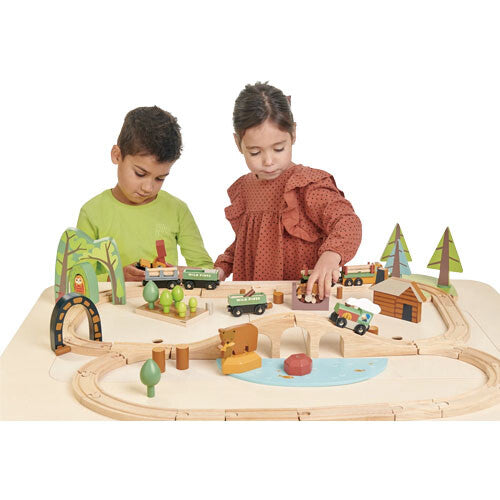 Twee kinderen spelen samen met de tender leaf toys houten treinbaan dennenbos op een tafel.
