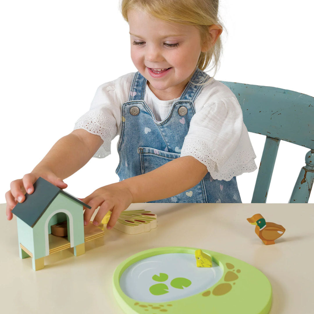 Een lachend kind speelt met de Tender Leaf Toys houten eendenfamilie speelset.