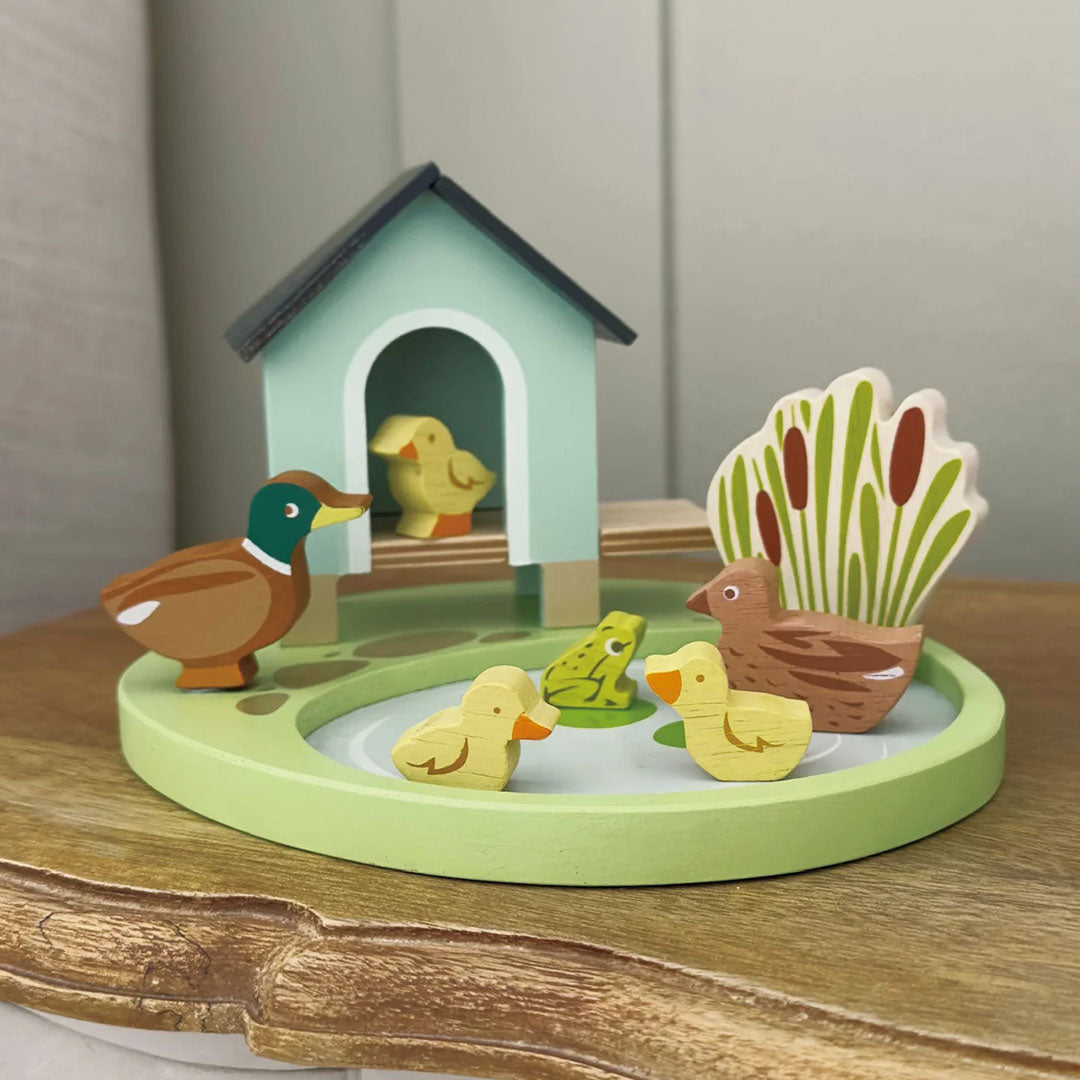 Tender Leaf Toys houten speelset met eendenhuis, vijver, eendenfamilie en kikker op een houten ondergrond.