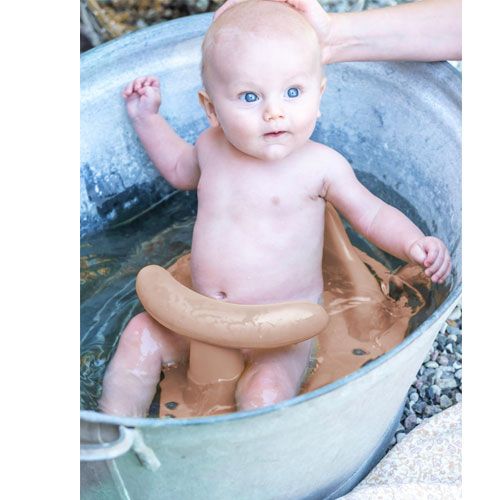Een baby zit in het bruine that's mine badzitje in een metalen badkuip met water.