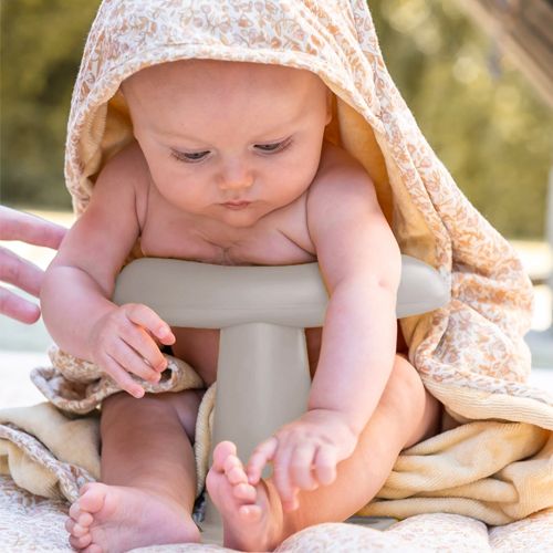 Baby zit in het That's Mine badzitje, gewikkeld in een handdoek.