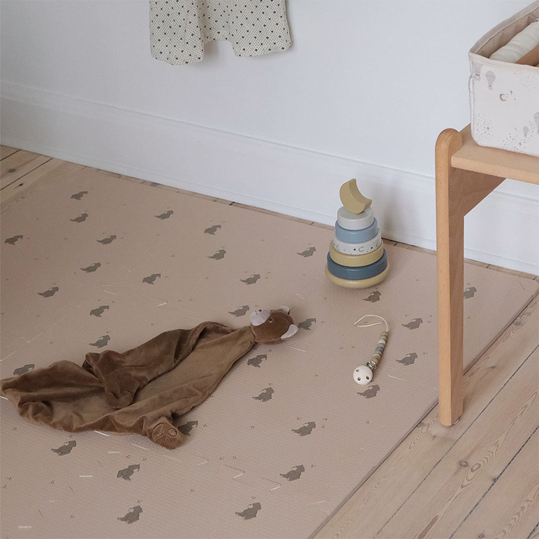 that's mine roze foam speelmat met beren en bijen patroon op een houten vloer, met babyspeelgoed.