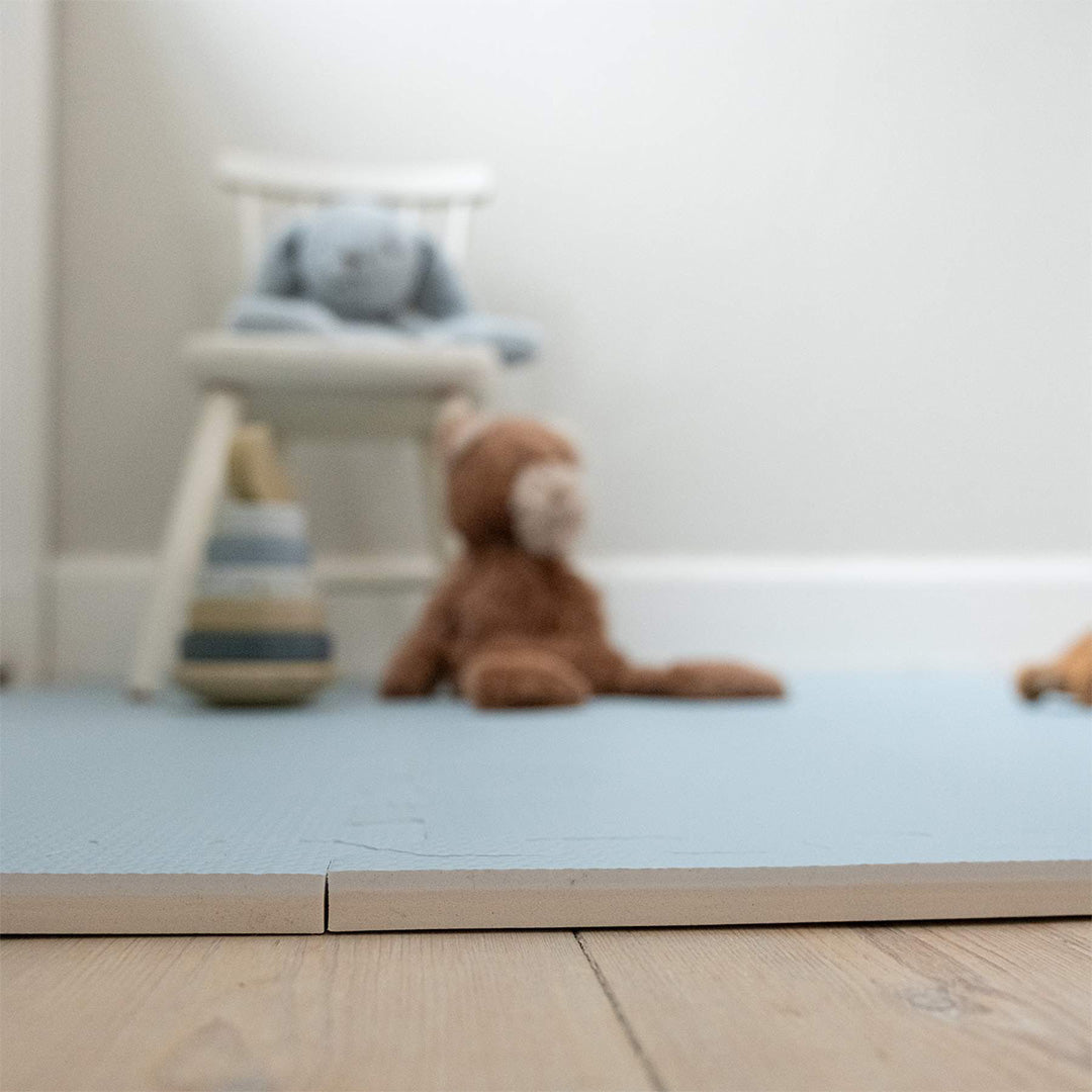 Close-up van de dikte en textuur van de that's mine lichtblauwe foam speelmat voor baby's op een houten vloer.
