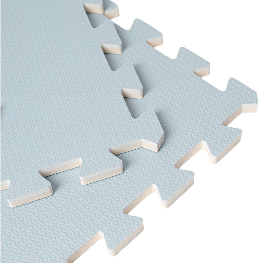 Close-up van de in elkaar grijpende puzzelranden van de that's mine lichtblauwe foam speelmat voor baby's, met zicht op de gelaagde structuur.