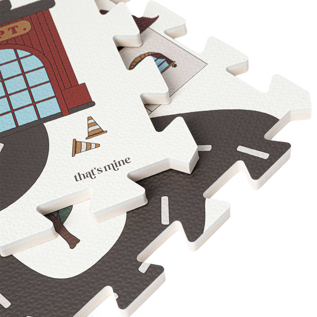 Detail van de in elkaar grijpende puzzelstukken van de that's mine foam speelmat met een weg en verkeerskegel.