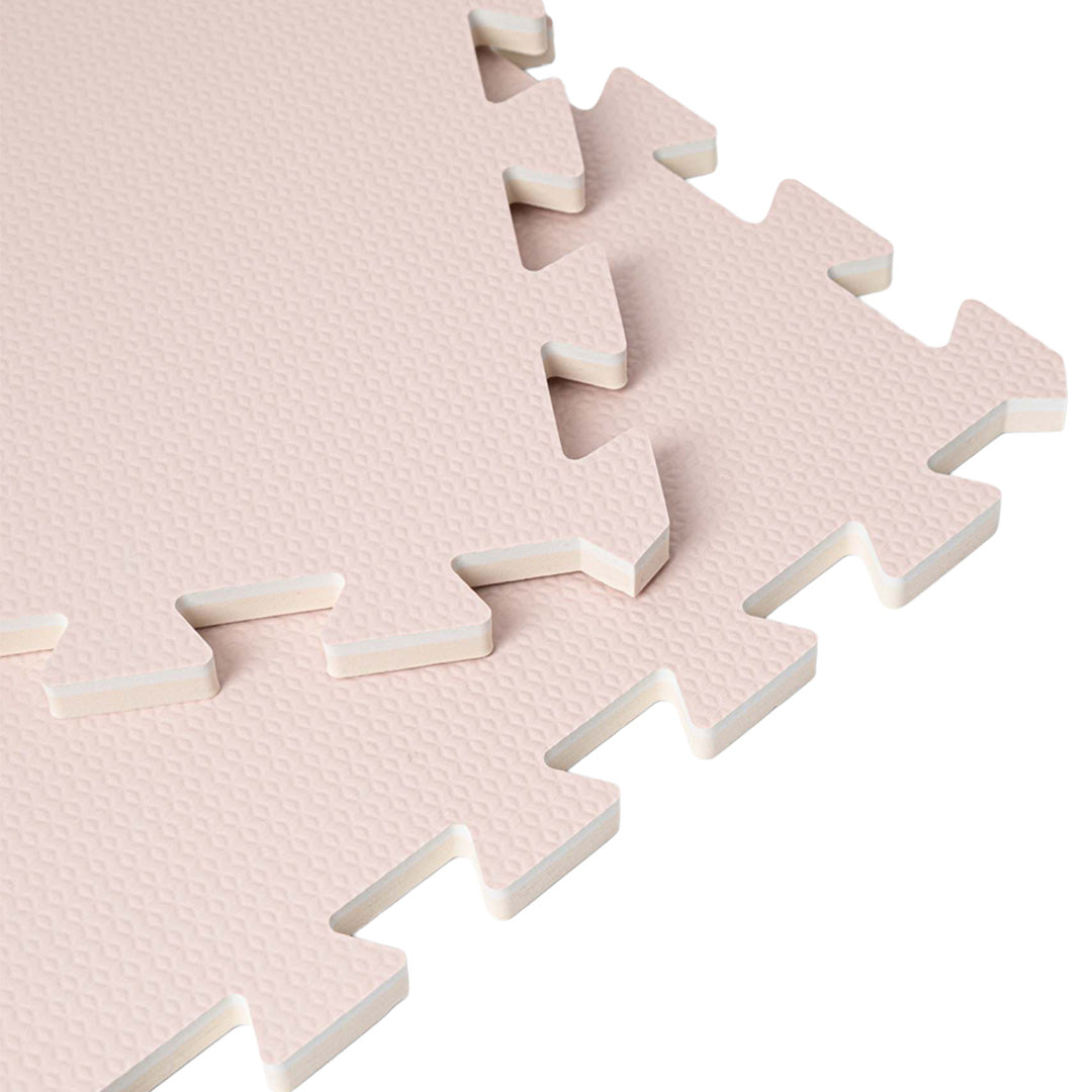 Detail van de in elkaar grijpende randen van een roze foam speelmat.