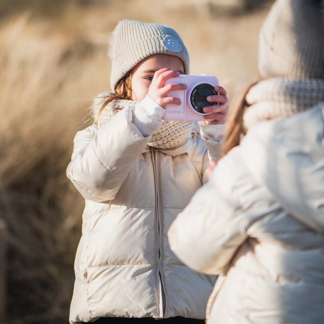 Een kind in winterkleding fotografeert met de roze The Zoofamily kindercamera met eenhoorn.