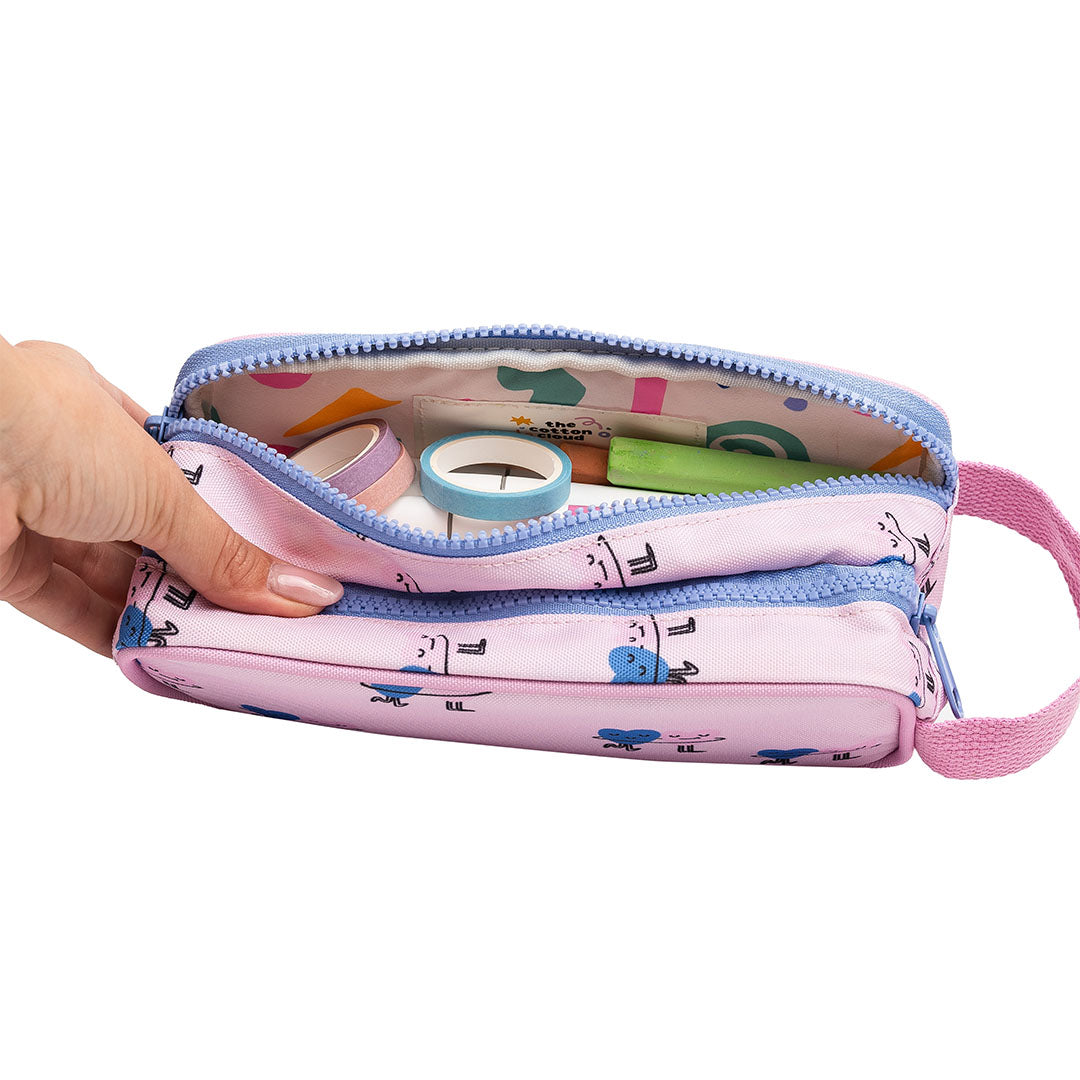 Een hand houdt een open The Cotton Cloud roze etui met dansende harten, gevuld met kantoorartikelen.