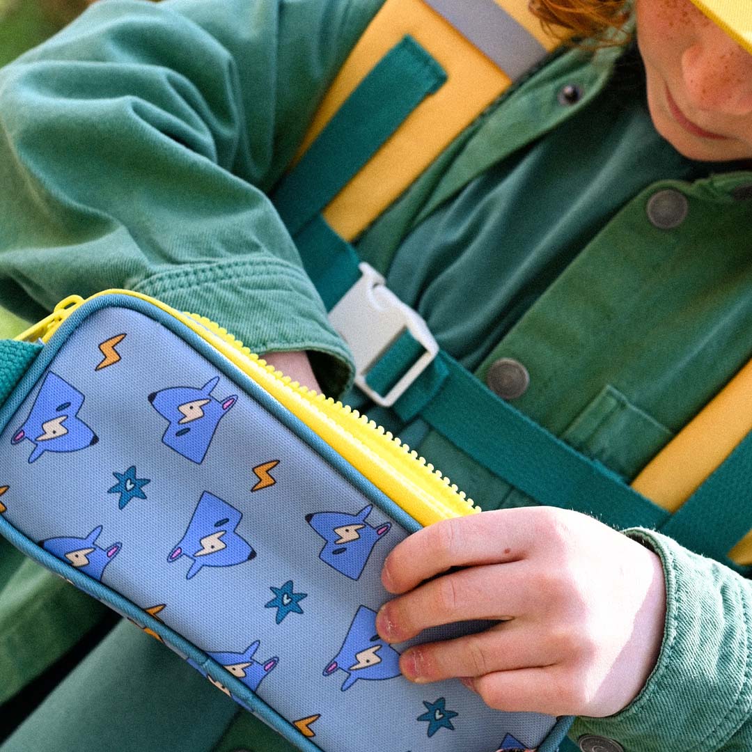 Kind houdt een blauw etui vast met een patroon van blauwe vossen en bliksemschichten.