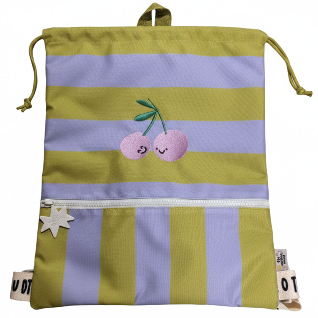 De the cotton cloud gym- en zwemtas Cherry Pop met gele en paarse strepen en geborduurde kersen met gezichtjes, plat neergelegd.